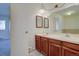 Double sink bathroom with two framed mirrors, a hanging light, and natural wood cabinetry at 13901 E Oxford Pl, Aurora, CO 80014