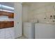 Laundry room with a white washer and dryer, open shelving, and an adjacent kitchen at 13901 E Oxford Pl, Aurora, CO 80014