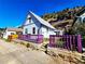 Charming cottage with a purple-trimmed porch nestled against a hillside, offering unique curb appeal and character at 1716 Virginia St, Idaho Springs, CO 80452