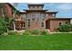 Beautiful backyard with a large lawn, mature trees, and an elegant house facade in view at 8044 E 24Th Ave, Denver, CO 80238
