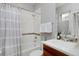 Cozy bathroom featuring gray walls, shower/tub with decorative curtain, and stylish hardwood vanity at 8044 E 24Th Ave, Denver, CO 80238