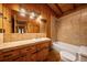 Bathroom features wooden cabinets, tile backsplash, and a shower-tub combo at 121 Mary Beth Rd, Evergreen, CO 80439