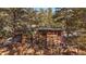 Cozy log cabin featuring a stone chimney, American flag, and plentiful firewood storage at 121 Mary Beth Rd, Evergreen, CO 80439