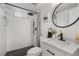 Modern bathroom featuring a tiled shower, black hardware, and a white vanity with a round mirror at 3541 Eudora St, Denver, CO 80207
