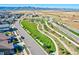 An aerial view of green spaces, streets, and houses in a neighborhood setting with mountain views beyond the development at 7267 Prairie Sage Pl, Littleton, CO 80125