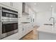 Kitchen with stainless steel appliances, white cabinets, quartz countertops, and center island at 7267 Prairie Sage Pl, Littleton, CO 80125
