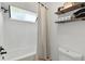All-white bathroom with a tub/shower, simple shelves, and a toilet at 6795 E Arizona Ave # B, Denver, CO 80224