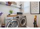 Functional laundry room with modern front load washer and dryer and storage at 8883 Ramblestone St, Highlands Ranch, CO 80129