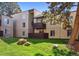 Building exterior features a grassy lawn with a balcony, a covered deck and large trees at 9995 E Harvard Ave # 221, Denver, CO 80231
