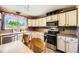 Well-lit kitchen with stainless steel appliances, tile countertops, and white cabinets at 11462 W Tennessee Pl, Lakewood, CO 80226