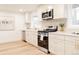 Contemporary kitchen with white cabinets, stainless steel appliances, and a view of the dining area at 4395 Newland St, Wheat Ridge, CO 80033