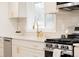 Modern kitchen featuring stainless steel appliances, white cabinetry with gold hardware, and a bright window above the sink at 4395 Newland St, Wheat Ridge, CO 80033
