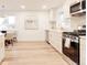 Well-lit kitchen with stainless steel appliances, white cabinets, a modern stove, and an adjacent dining area at 4395 Newland St, Wheat Ridge, CO 80033