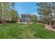 Expansive backyard featuring a lush lawn, mature trees, a patio with outdoor seating, and a fenced perimeter at 12430 S Downy Creek Ct, Parker, CO 80134