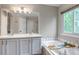 Bright bathroom featuring a double sink vanity, bathtub, and large mirror reflecting natural light from the window at 12430 S Downy Creek Ct, Parker, CO 80134