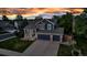 Charming two-story home with a three-car garage and manicured front lawn set against a colorful sunset sky at 12430 S Downy Creek Ct, Parker, CO 80134