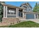 Charming front porch with decorative pillars and a well-manicured lawn leading to a three-car garage at 12430 S Downy Creek Ct, Parker, CO 80134