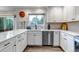 Contemporary kitchen boasting white cabinets, stainless steel dishwasher, and ample counter space at 12430 S Downy Creek Ct, Parker, CO 80134