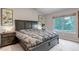 Serene main bedroom featuring a king-size bed, nightstands, and a bright window overlooking green scenery at 12430 S Downy Creek Ct, Parker, CO 80134