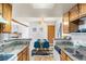 Bright dining room with a glass table, blue chairs and kitchen in the background, illuminated by a skylight at 942 S Walden St # 204, Aurora, CO 80017