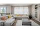 Bright living room featuring a white sectional sofa with colorful pillows and a patterned ottoman at 27029 E Irish Pl, Aurora, CO 80016