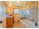 Well-lit bathroom featuring a soaking tub with decorative tile surround and vanity with granite countertop at 430 Long View Ct, Longmont, CO 80501