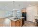 Bright, modern kitchen with a granite island, stainless steel sink, wood cabinets, and gray flooring at 17962 E 103Rd Ave, Commerce City, CO 80022