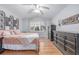 This is a bedroom with wood floors, white walls, a ceiling fan, and a bed with decorative pillows and bedding at 13545 W 62Nd Ln, Arvada, CO 80004