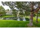 Community pond with mature trees, green lawns and building in the distance at 13545 W 62Nd Ln, Arvada, CO 80004