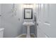 Tastefully decorated powder room with a pedestal sink, stylish mirror, and updated lighting fixtures at 13545 W 62Nd Ln, Arvada, CO 80004