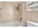 A neutral tone tiled shower and bath with a shower caddy and open shelving for storage at 2838 Decatur St, Denver, CO 80211
