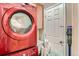 Laundry room with a red washer and dryer, white door and a modern, mounted vacuum cleaner at 2838 Decatur St, Denver, CO 80211