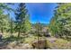 Exterior view features a well-maintained home nestled among mature trees and boulders with scenic mountain views at 31762 Horseshoe Dr, Evergreen, CO 80439