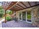 Outdoor patio with stone floor, wooden pergola, rock landscaping, and sliding glass doors at 16134 Sandstone Dr, Morrison, CO 80465