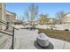 A spacious backyard with a concrete patio, modern outdoor seating, fire pit, and newly planted trees and privacy fence at 5072 Cathay St, Denver, CO 80249