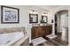 Bathroom boasts a soaking tub, double vanity with granite counters and wooden cabinets at 5072 Cathay St, Denver, CO 80249