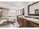 Bathroom with double vanity, soaking tub, glass shower, and travertine tile at 5072 Cathay St, Denver, CO 80249