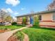 Charming brick home with a lush green lawn, mature landscaping, and a welcoming blue door at 4201 Shoshone St, Denver, CO 80211