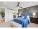 Stylish bedroom featuring a blue accent wall, plush bedding, and a sliding barn door leading to the bathroom at 2248 S Lincoln St, Denver, CO 80210