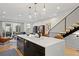 Open concept kitchen with island seating, stainless steel appliances, view to the living area, and modern staircase at 2248 S Lincoln St, Denver, CO 80210
