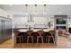 Modern kitchen with stainless steel appliances, white cabinets, kitchen island, wooden stools, and globe pendant lighting at 2248 S Lincoln St, Denver, CO 80210