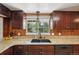 Kitchen sink area with decorative backsplash, granite countertops, and dark wooden cabinets at 3285 W 11Th Avenue Ct, Broomfield, CO 80020