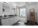 Bright bathroom featuring a double vanity with granite counters, tub, and natural light at 3275 W Hawthorne Pl, Denver, CO 80221
