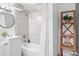 Clean and modern bathroom featuring neutral tile, a shower tub combo, and decorative shelving at 3275 W Hawthorne Pl, Denver, CO 80221