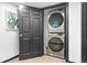 Modern laundry room with stacked washer and dryer behind a black painted door at 3275 W Hawthorne Pl, Denver, CO 80221