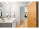 Bright bathroom featuring modern sink, light wood door, and an open view to the bedroom at 3100 Huron St # 1B, Denver, CO 80202