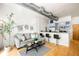 Living room with a gray sofa facing a kitchen with stainless steel appliances and bar seating at 3100 Huron St # 1B, Denver, CO 80202