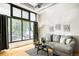 Bright living room with large windows, a gray sofa, and stylish artwork on the wall at 3100 Huron St # 1B, Denver, CO 80202