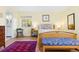 A well-lit bedroom showcases a wooden bed frame with a stylish blue patterned bench and a red rug at 15000 W 29Th Ave, Golden, CO 80401