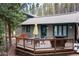Back deck featuring outdoor furniture, umbrella, and a grill with a forested backdrop at 446 Blue River Rd, Breckenridge, CO 80424